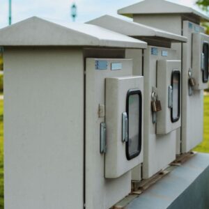 Close-up of locked electric boxes outdoors, featuring metal cabinets on a platform.